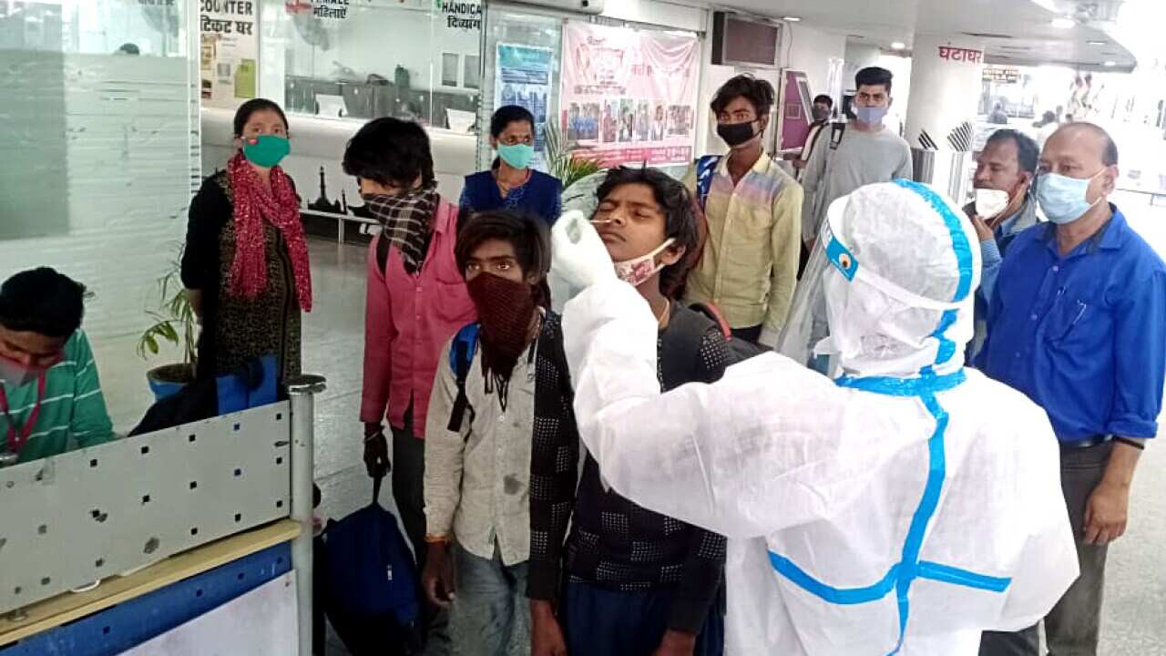 Healthcare workers in PPE kit collects swab samples for COVID-19 testing from passengers