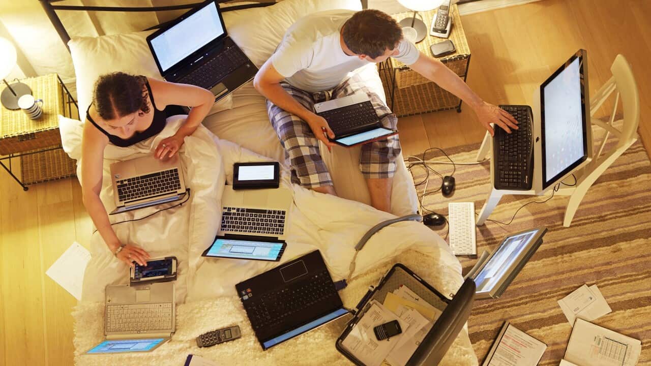Couple in bed surrounded by computers