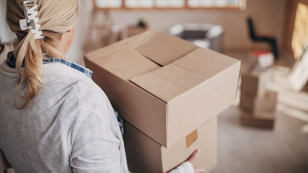 A woman carrying moving boxes.
