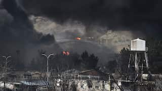 Thick black smoke surrounds buildings and oil infrastructure as several fires burn