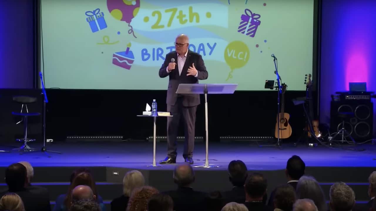 A man stands on a stage with a microphone.