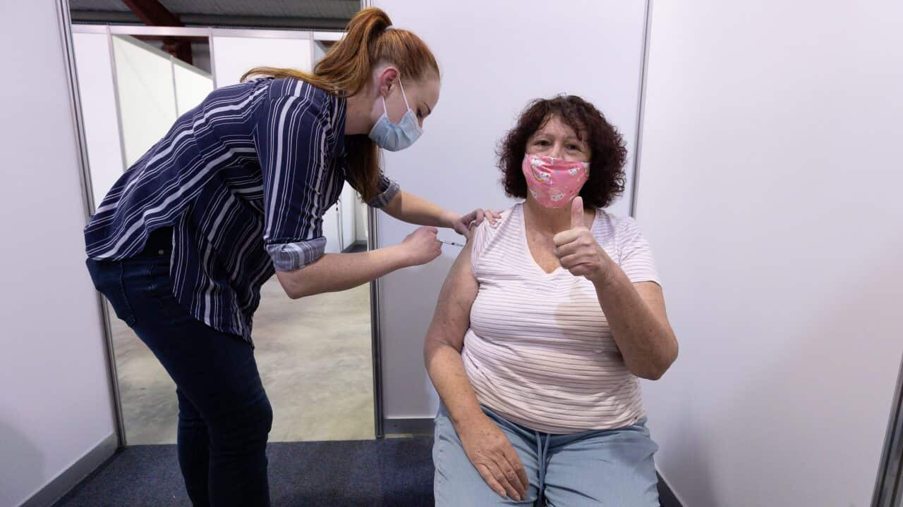 A woman gets her AstraZeneca vaccine from a nurse at the Claremont Showground mass vaccination centre in Perth.