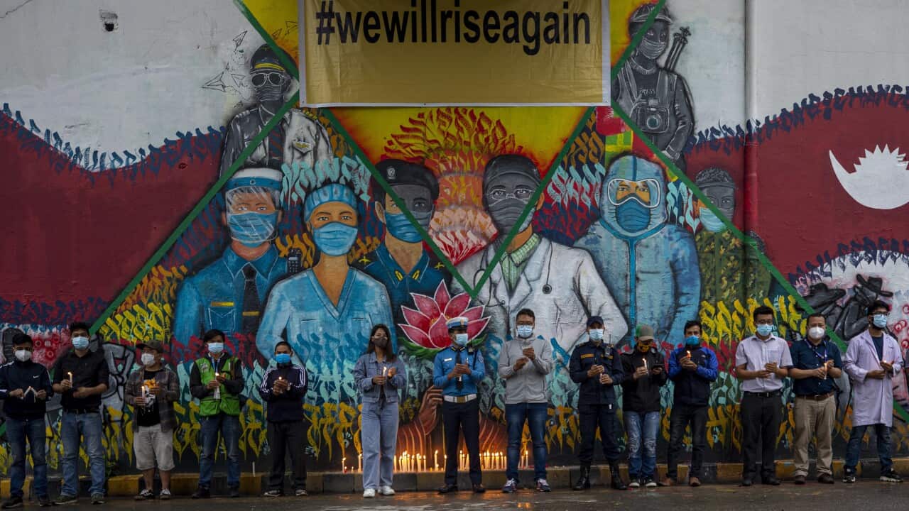Nepalis take part in a candle light vigil in Kathmandu to pay respect to people who have died due to the coronavirus