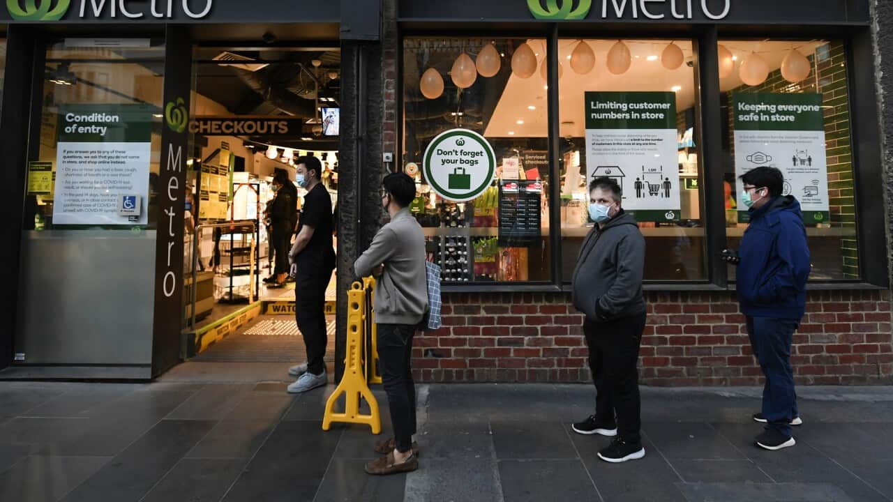 Customers line up at a supermarket before curfews begin