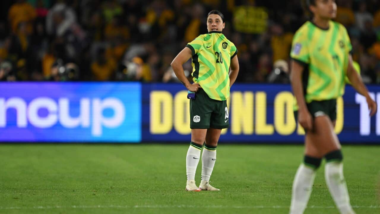 Two football players stand on the pitch wearing yellow and green jerseys