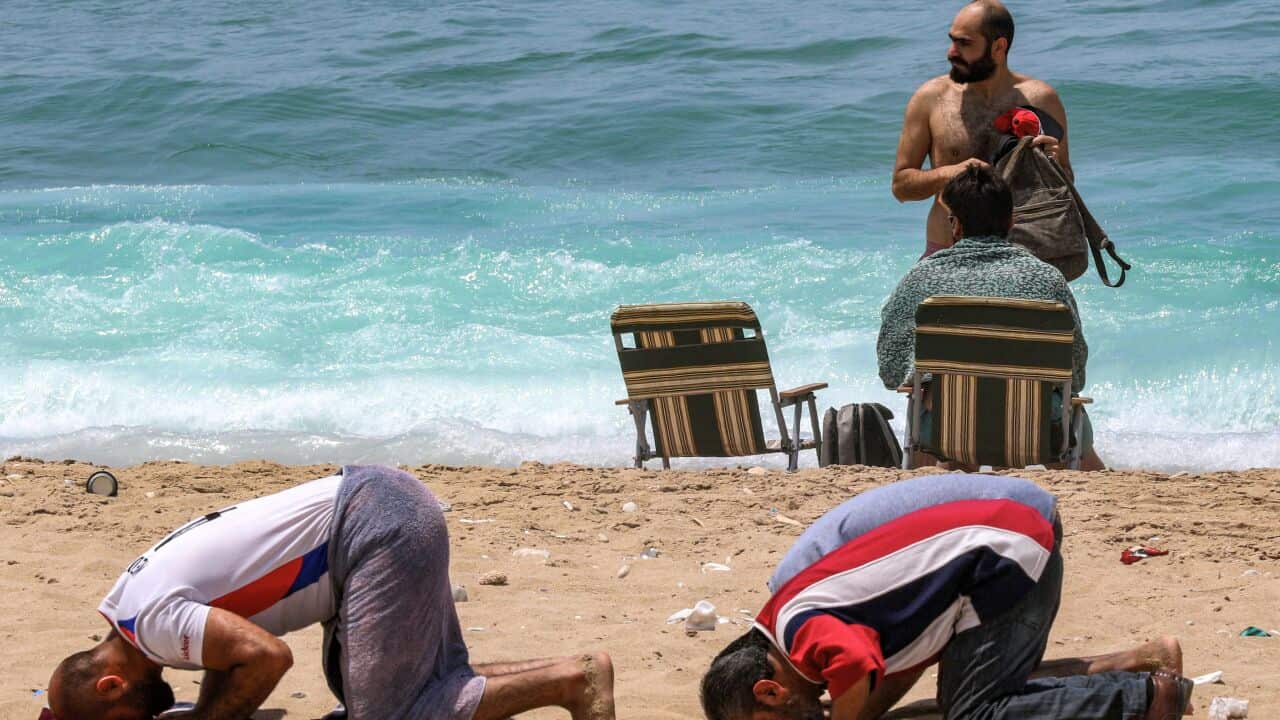 Two men praying on a beach in Lebanon's southern city of Sidon.