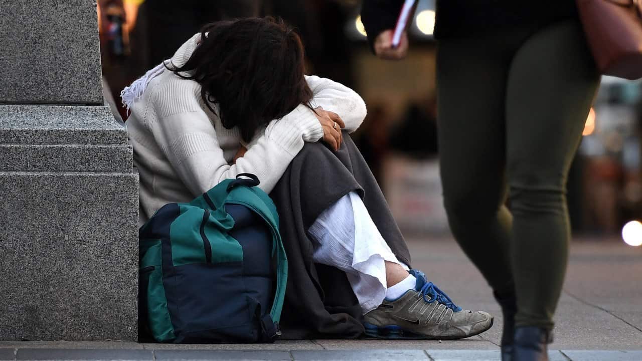 A homeless woman sits on a street corner in central Brisbane.