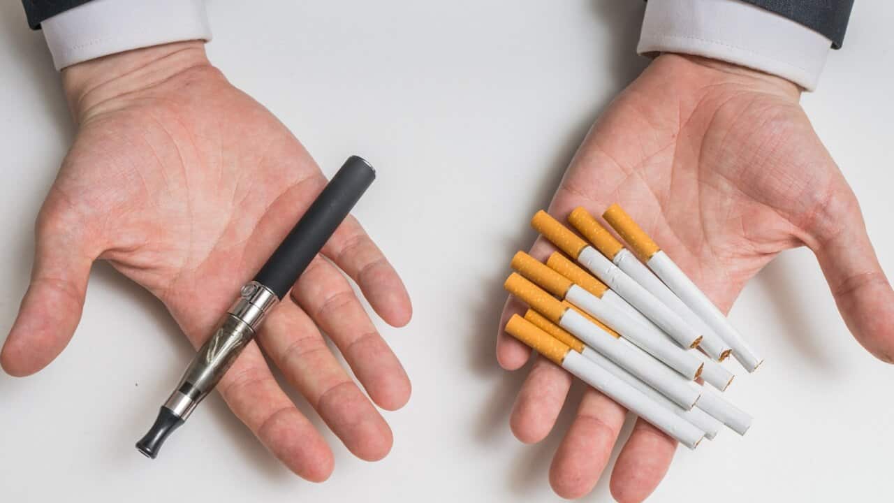 Hands holding electronic and conventional tobacco cigarettes and comparing.