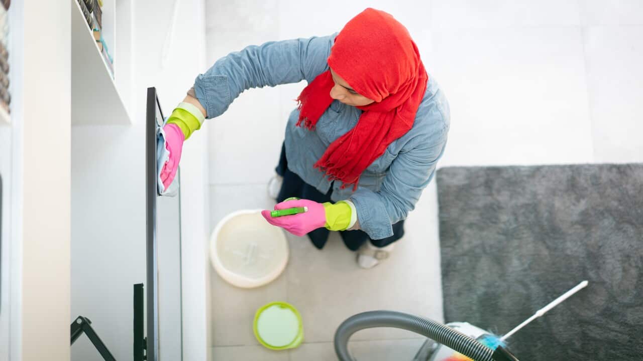 A woman with a head scarf over her head cleaning a house.