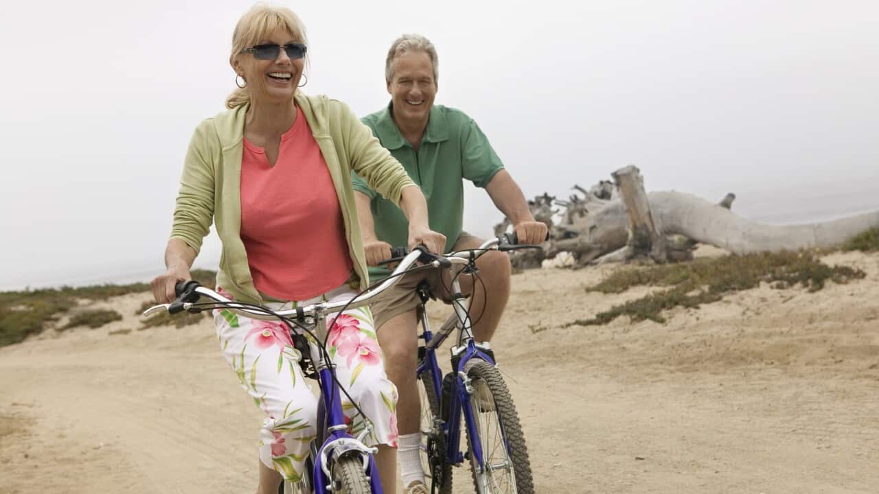 Old couple seniors riding bicycles along beach AAP