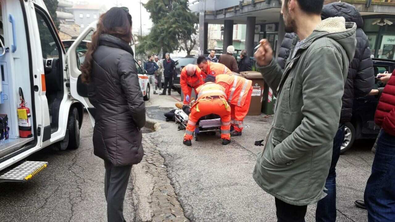 Paramedics treat an injured person who was shot from a passing vehicle in Macerata.