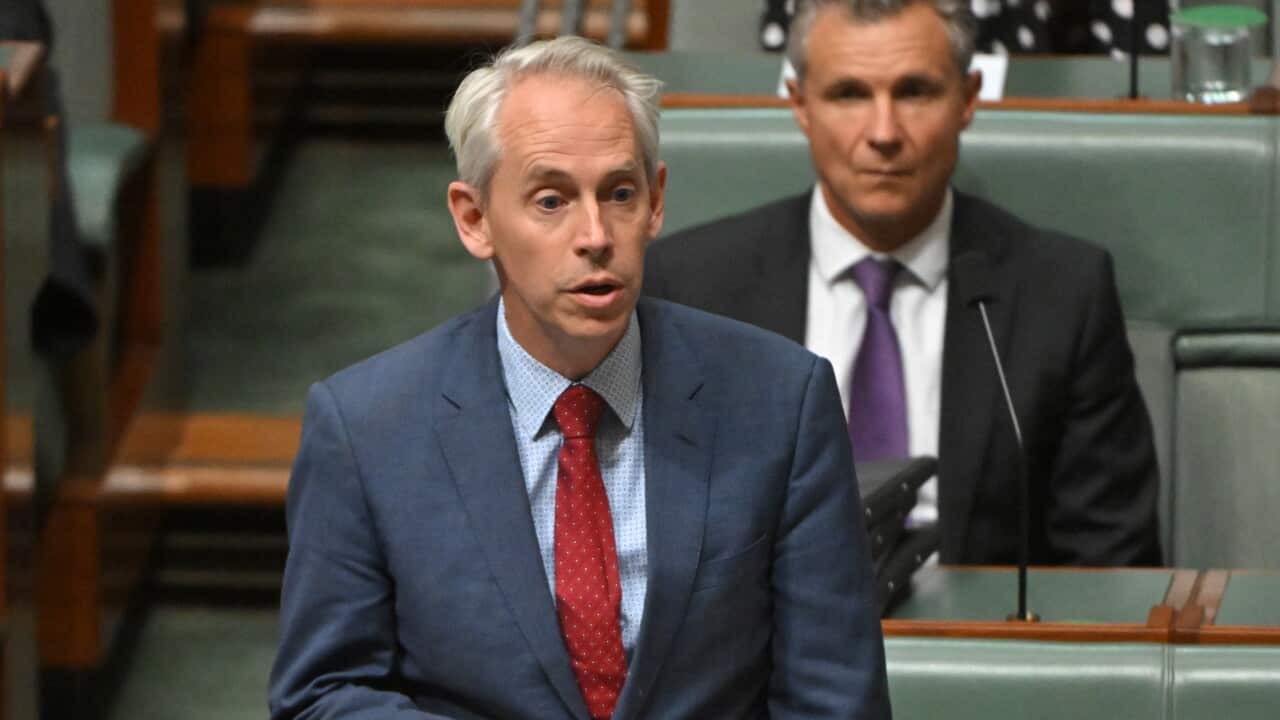 Andrew Giles wearing a suit and tie standing and speaking in the House of Representatives.