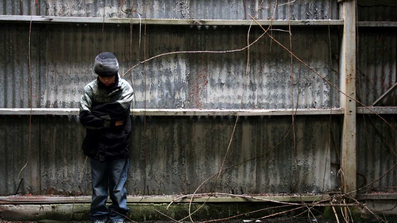 Boy Standing in Grunge Alleyway Against Abandoned Building