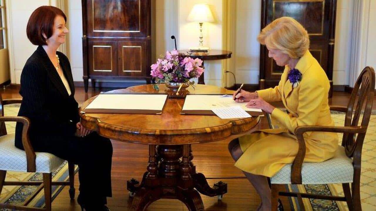 Julia Gillard (left) watches as Governor General Quentin Bryce signs her commission as Prime Minister of Australia at government House Canberra, Thurssday, June 24 2010.