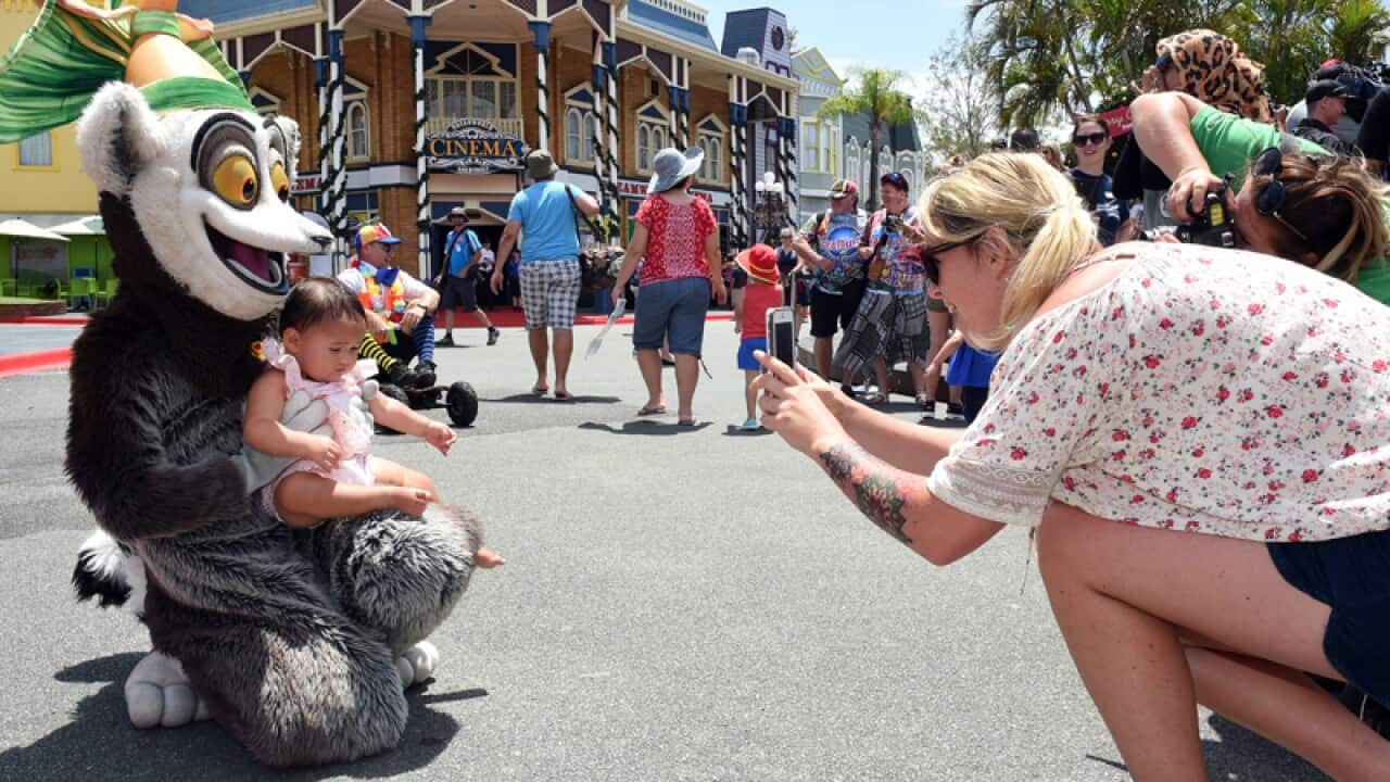 A mother takes a photo of her daughter with a cartoon character