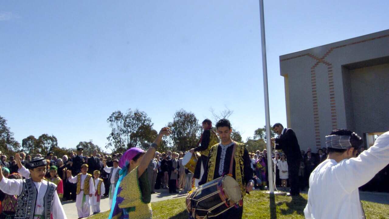 Canberra, August 18, 2005. Afghan dancers circle as the Afghanistan flag flies for the first time at the opening of the Afghanistan embassy in Canberra today. (AAP Image/Alan Porritt) NO ARCHIVING