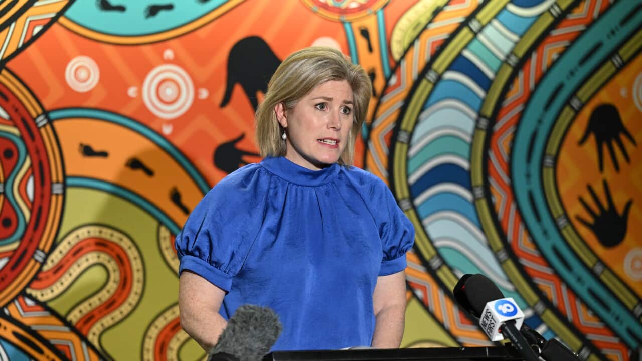 A woman in a blue top speaks at a press conference.