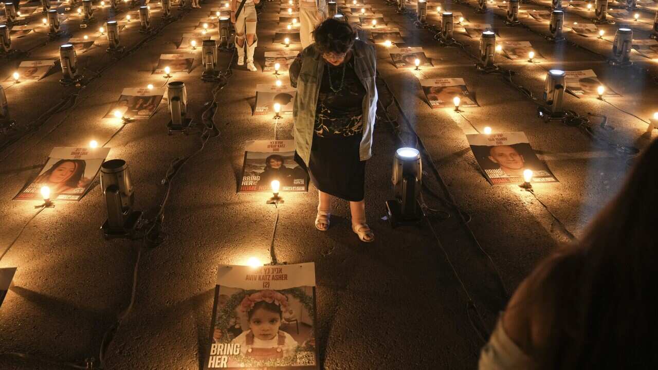 People walk between posters of hostages abducted by Hamas militants in Gaza, in Jerusalem, Sunday, Oct. 29, 2023.