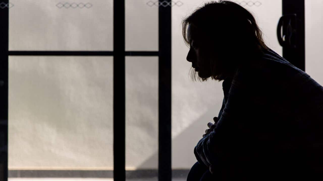 A silhouette of a woman in front of a glass door that leads outside.