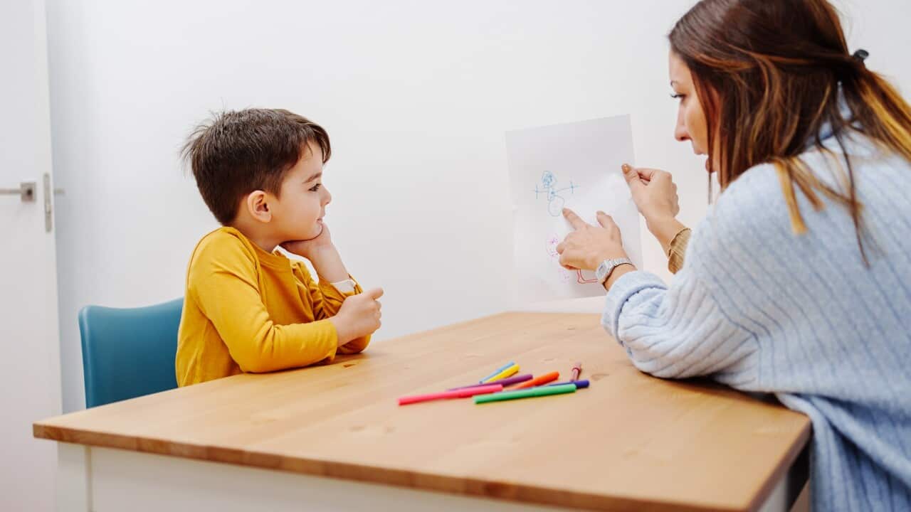 Psychology exercise for children, kid drawing family together with young educational therapist