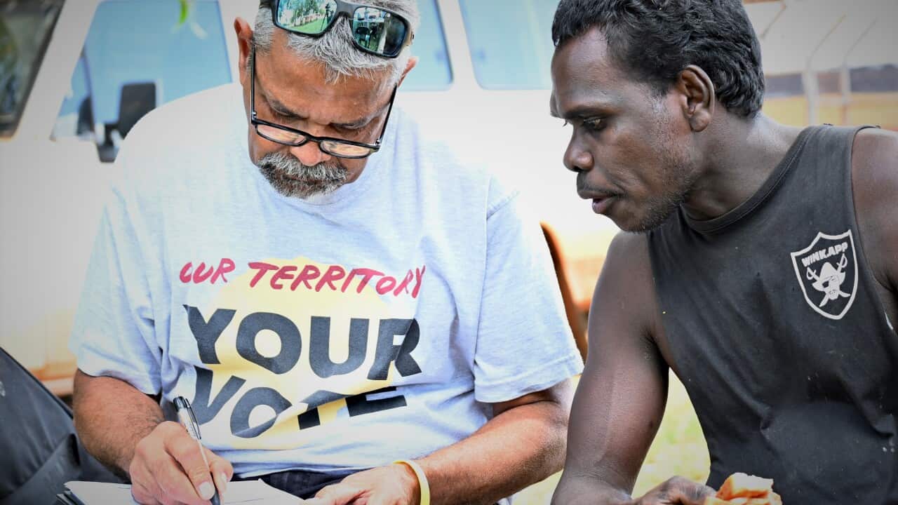 Noongar man Neville Kahn from the NT Electoral Commission talks to Ramingining Artist Daniel Warrulukuma about the upcoming election