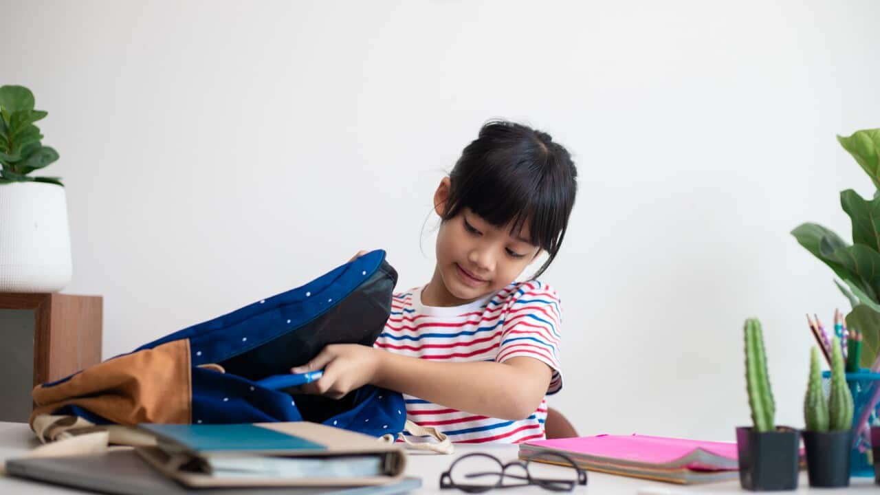 Primary school girl packs their school bags, preparing for school.