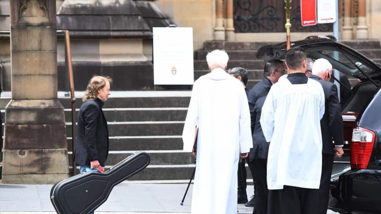 Angus Young watches as his brother Malcolm's casket is carried away
