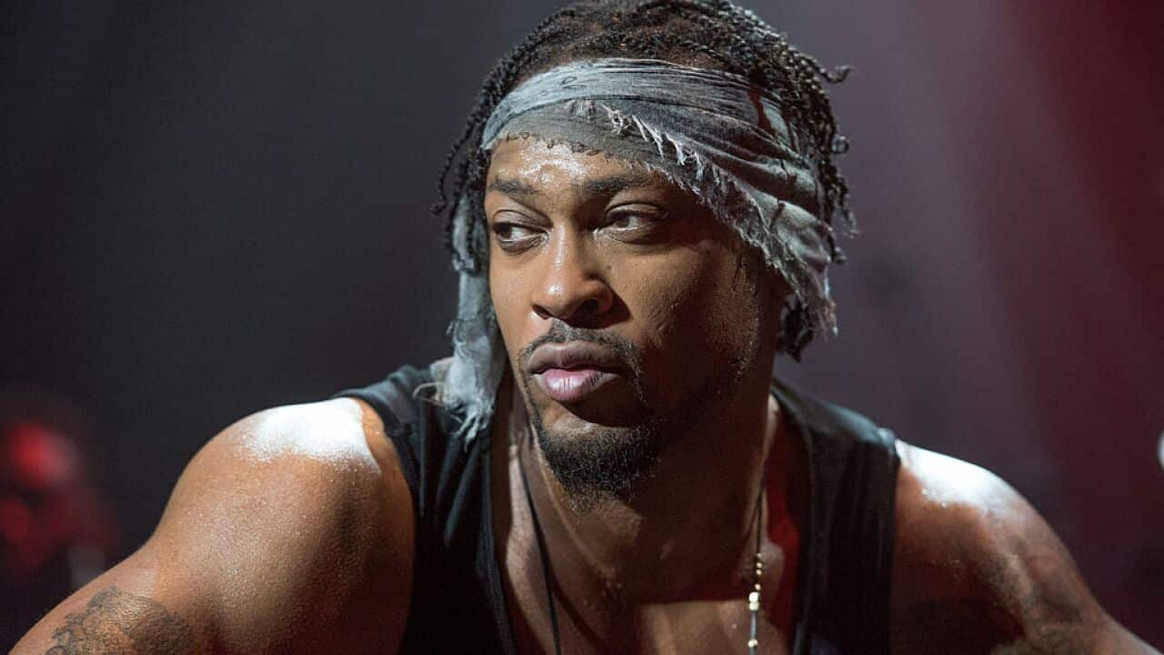 A man in a bandana looks to the side with a sultry expression on his face.