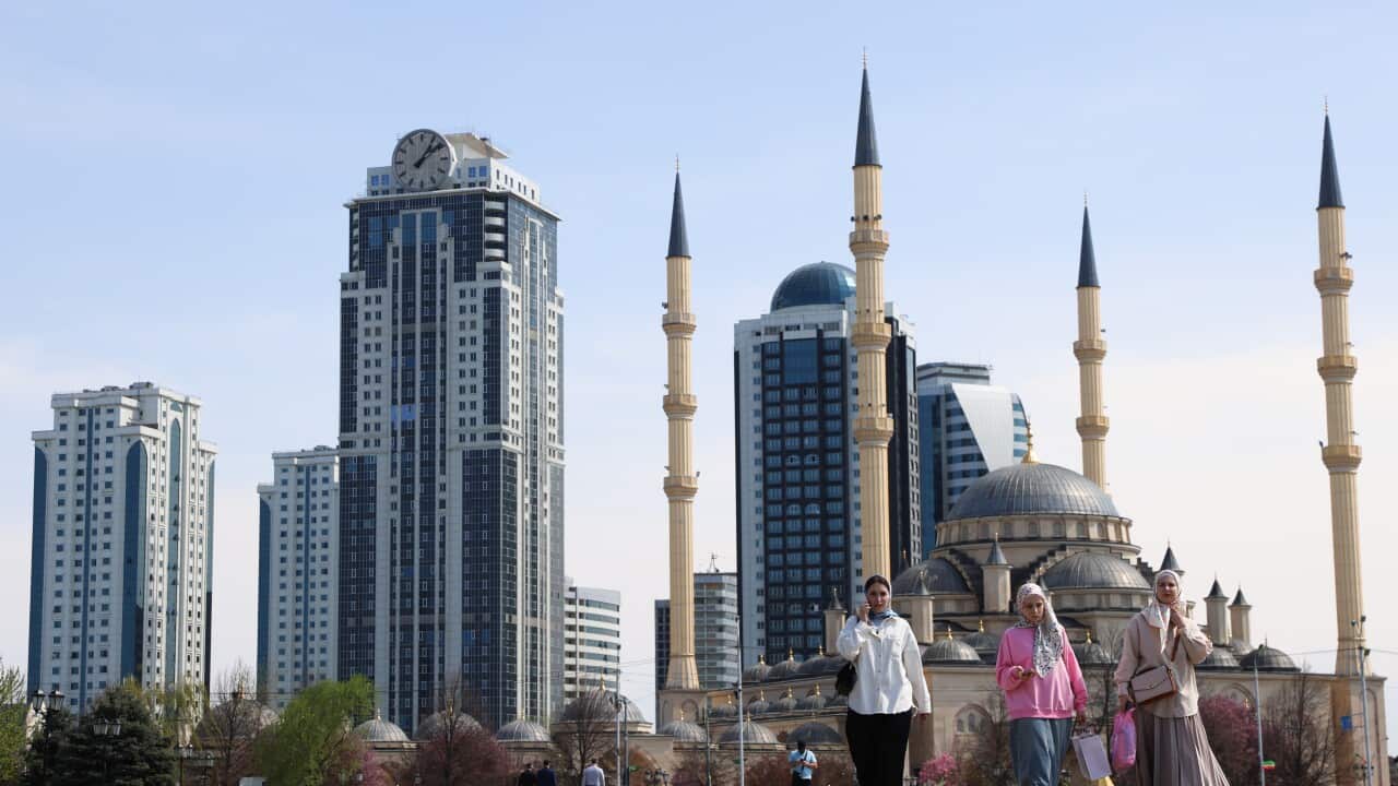People walking in front of skyscrapers and a mosque