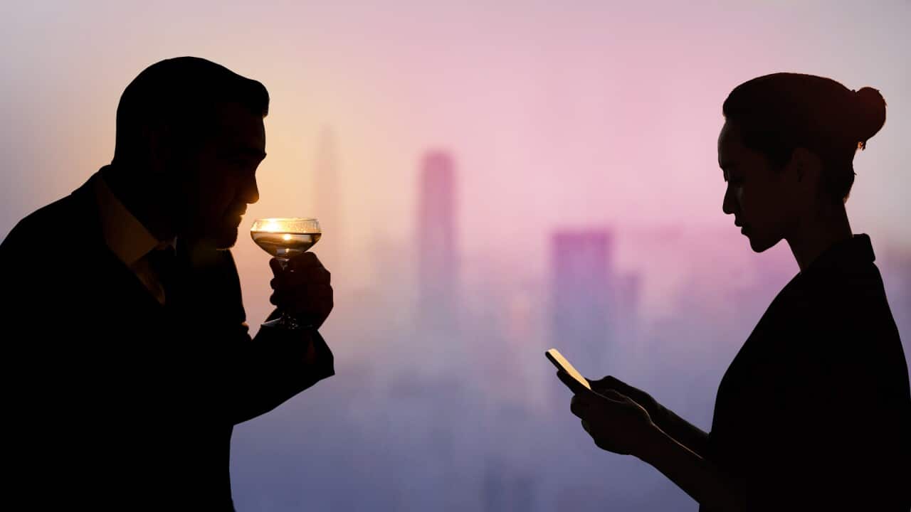 Silhouette of a man drinking a cocktail and a woman on her phone.