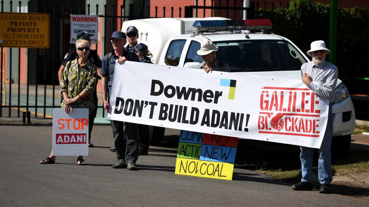 Protesters opposing the Adani coal mine hold signs outside the Downer Rail workshop during a visit by Premier Annastacia Palaszczuk on September 11, 2017.