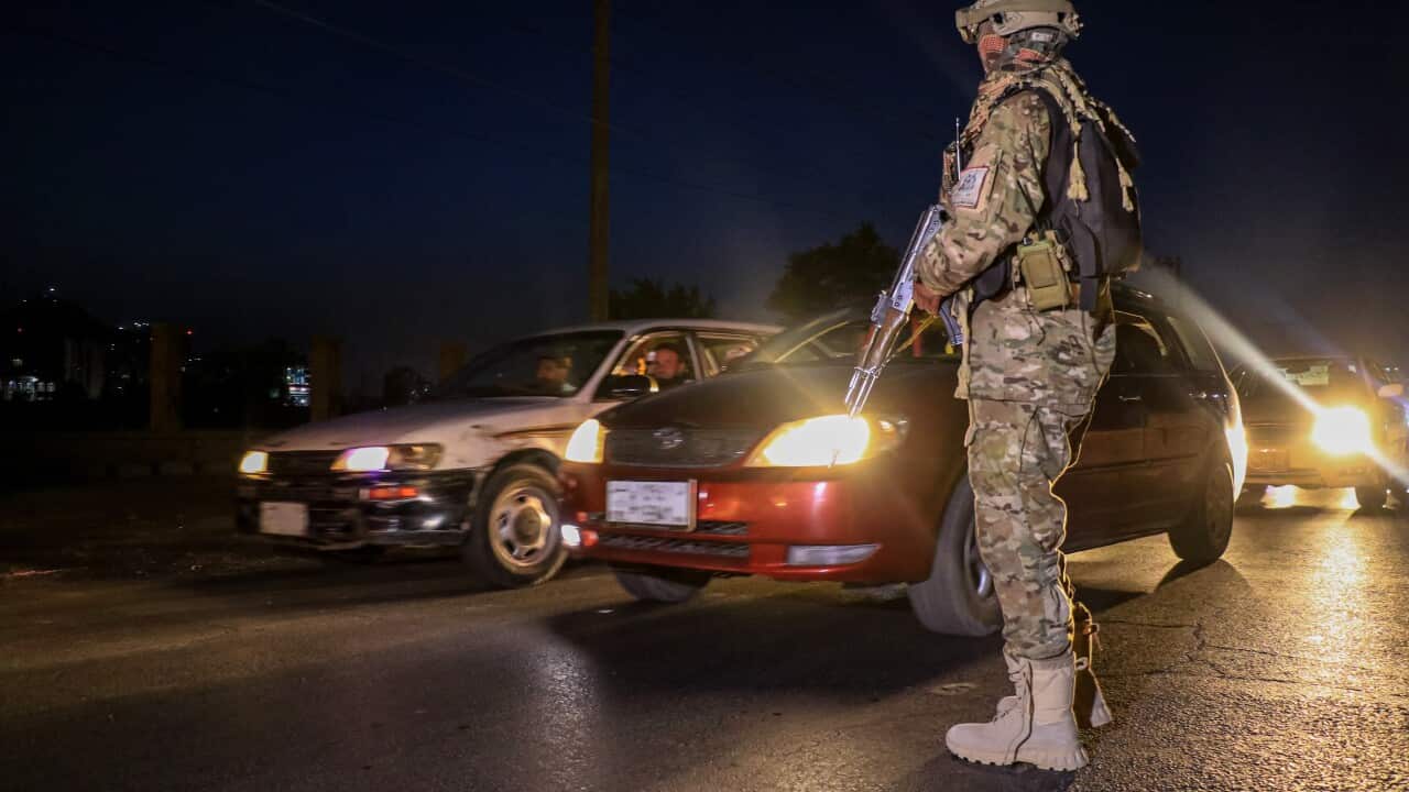 An officer standing on the road, wearing military uniform, as cars go past.