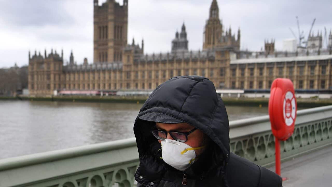 A man wearing a protective face mask walks past Westminster Palace parliament in London, Britain, 18 March 2020.