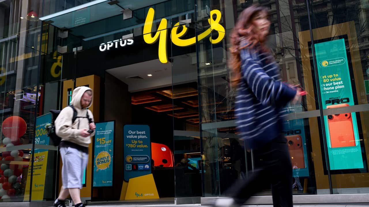 The entrance to an Optus shop as people walk past on a foothpath.