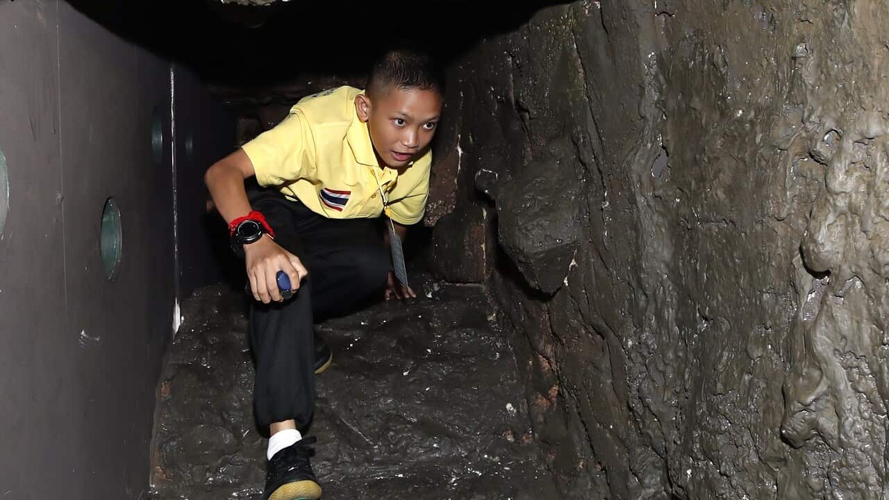 Mongkol Boonpiam, a rescued member of Wild Boar youth soccer team crawls inside a mock Tham Luang cave at the exhibition.