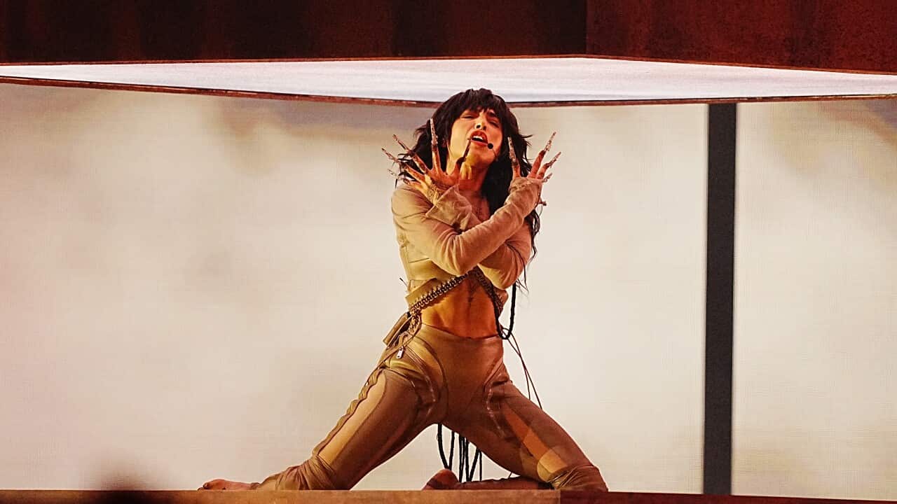 A woman in costume kneeling on stage.