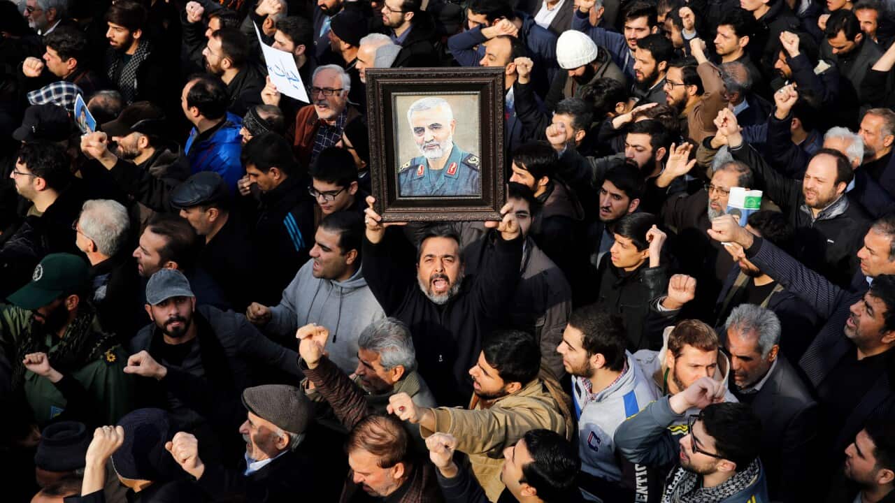 Iranians hold a portrait of Qasem Soleimani as they take to the streets to mourn his death