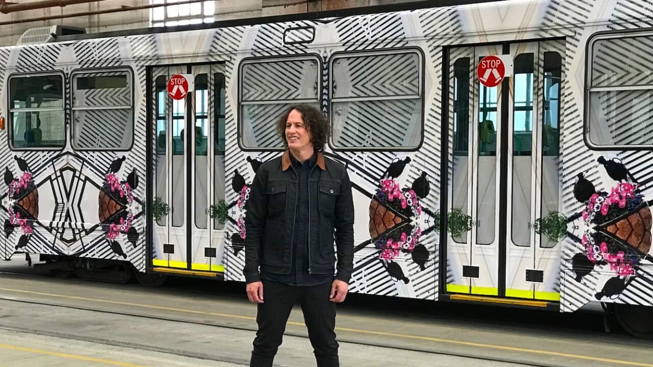 Kent Morris next to a tram featuring his artwork