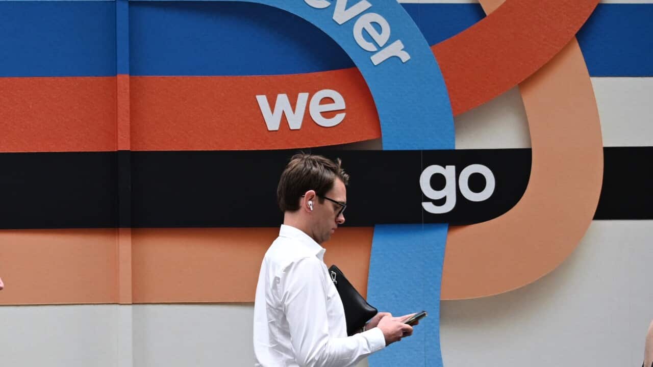 A side-on photo of a man walking past a mural that says 'wherever we go'
