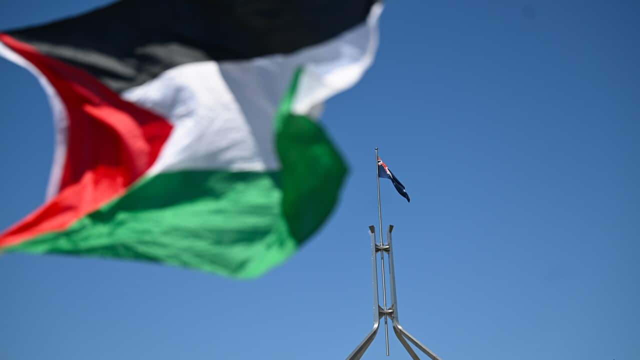 Una bandiera palestinese sventola di fronte a quella australiana sulla Parliament House a Canberra durante una manifestazione contro l'occupazione della Palestina.