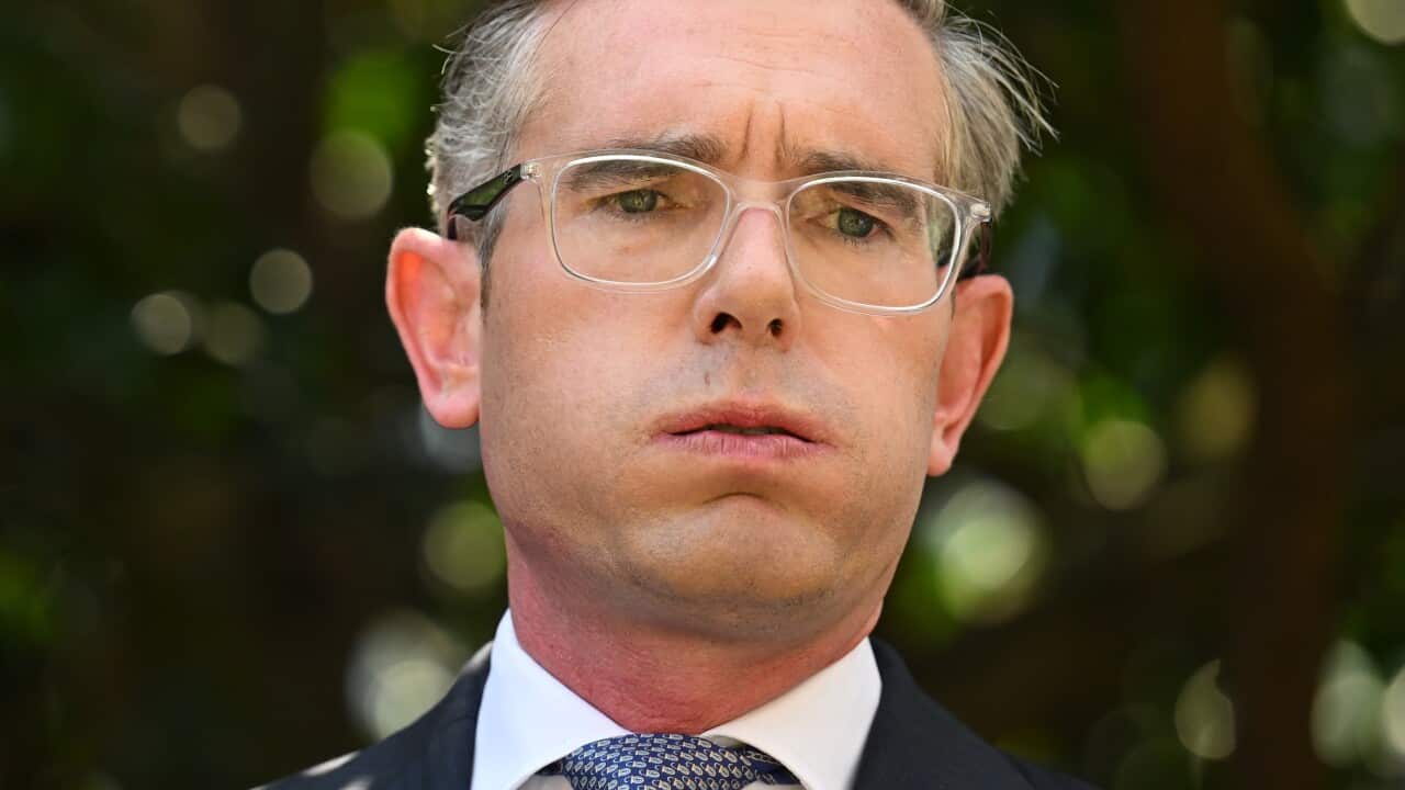 A man wearing a suit, tie, and glasses standing outside.