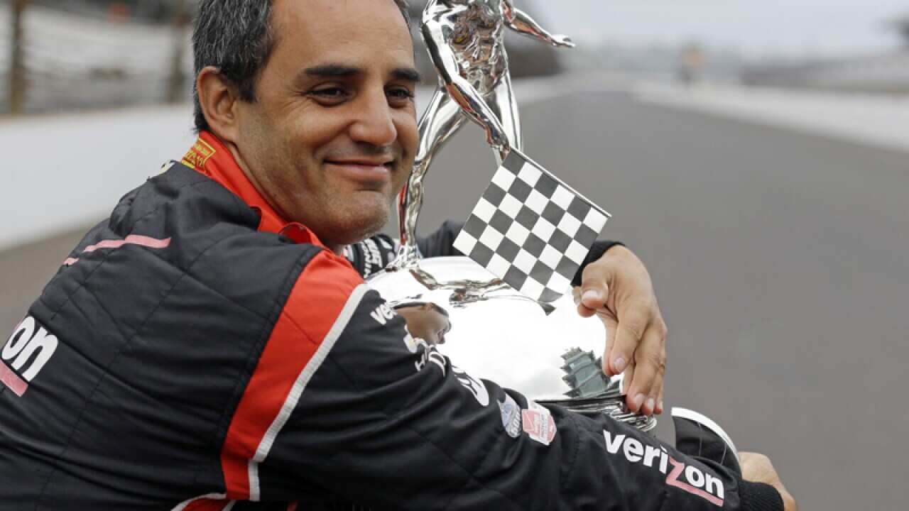 Juan Pablo Montoya, of Colombia, hugs the Borg-Warner Trophy