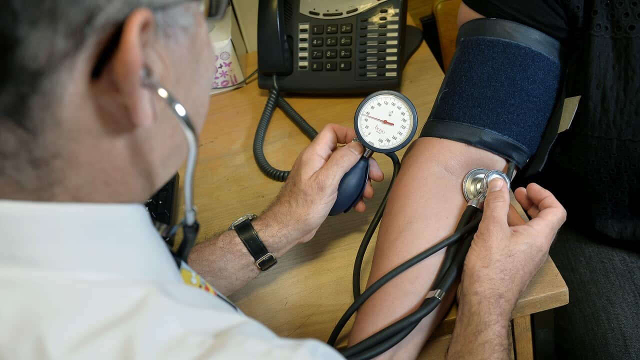 The doctor is checking the patient's blood pressure. The patient's face is not visible, only their hand.