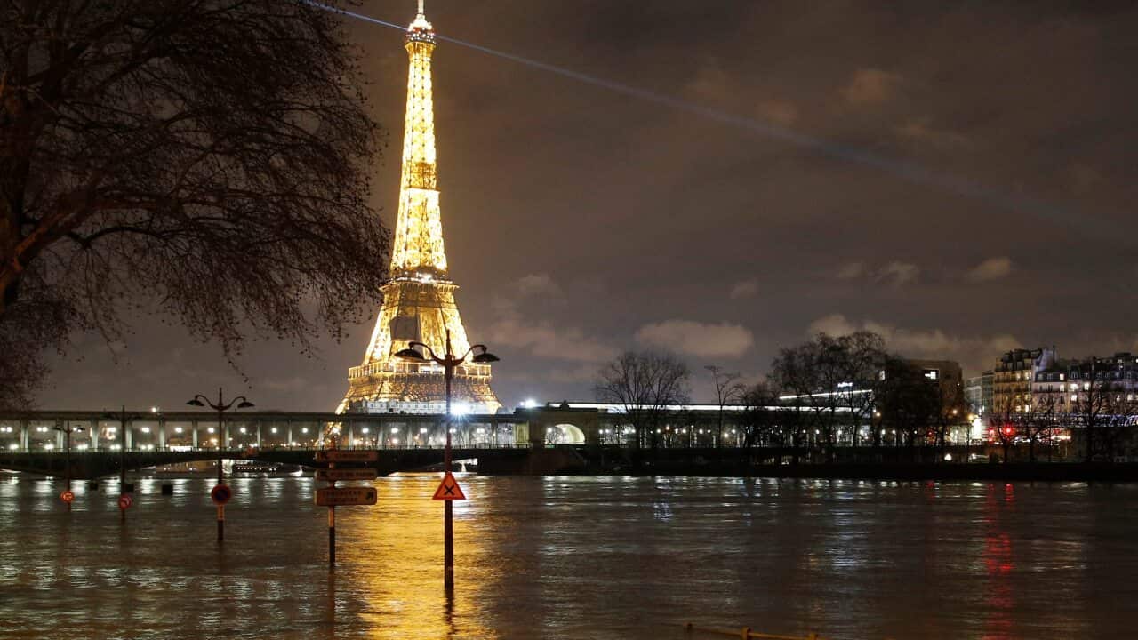 The Eiffel Tower and signboards are pictured next to the River Seine in Paris.