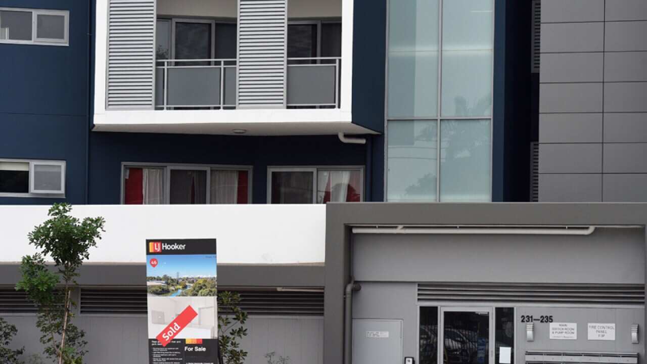 A for sale sign outside an apartment complex