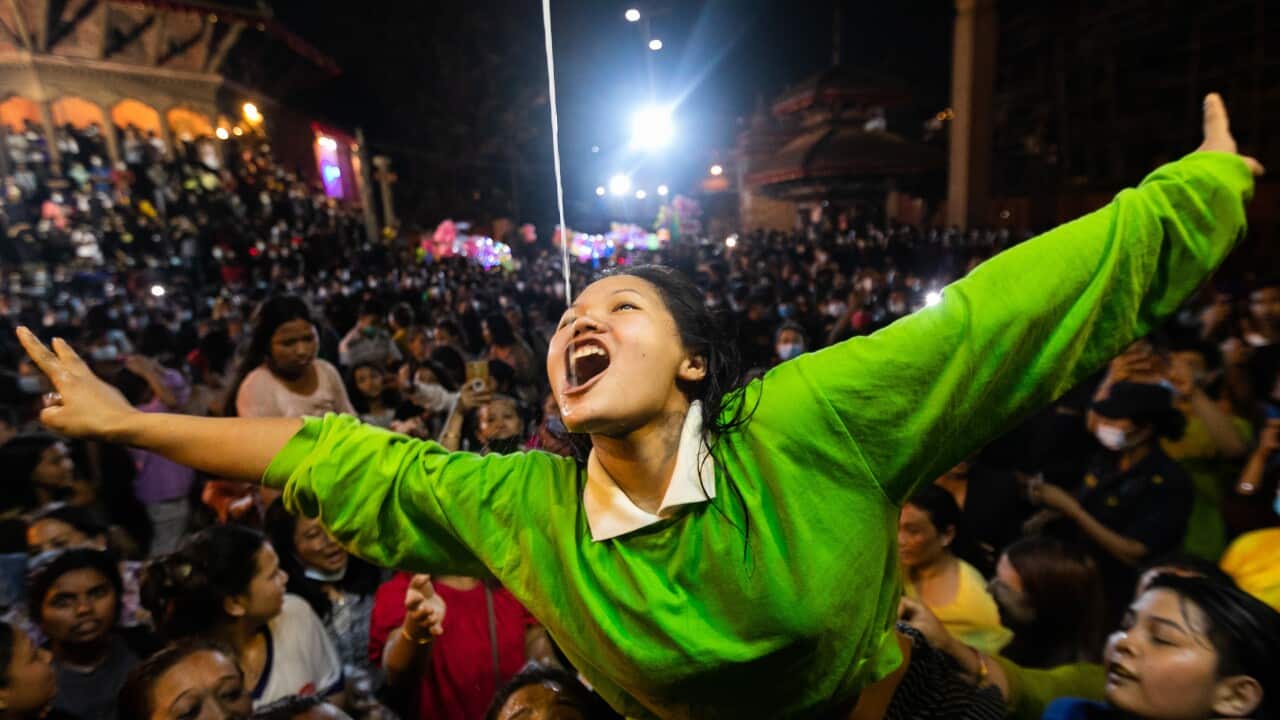 Nepalese women struggle to drink homemade alcohol from the mouth of Deity Swet Bhairav as blessings during Indra Jatra festival.
