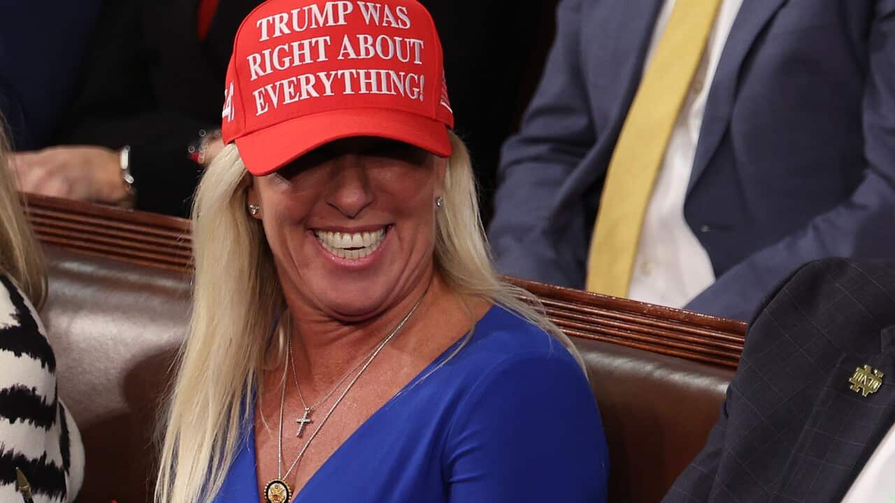 Marjorie Taylor Greene beaming and wearing a red “Trump was right about everything“ cap.