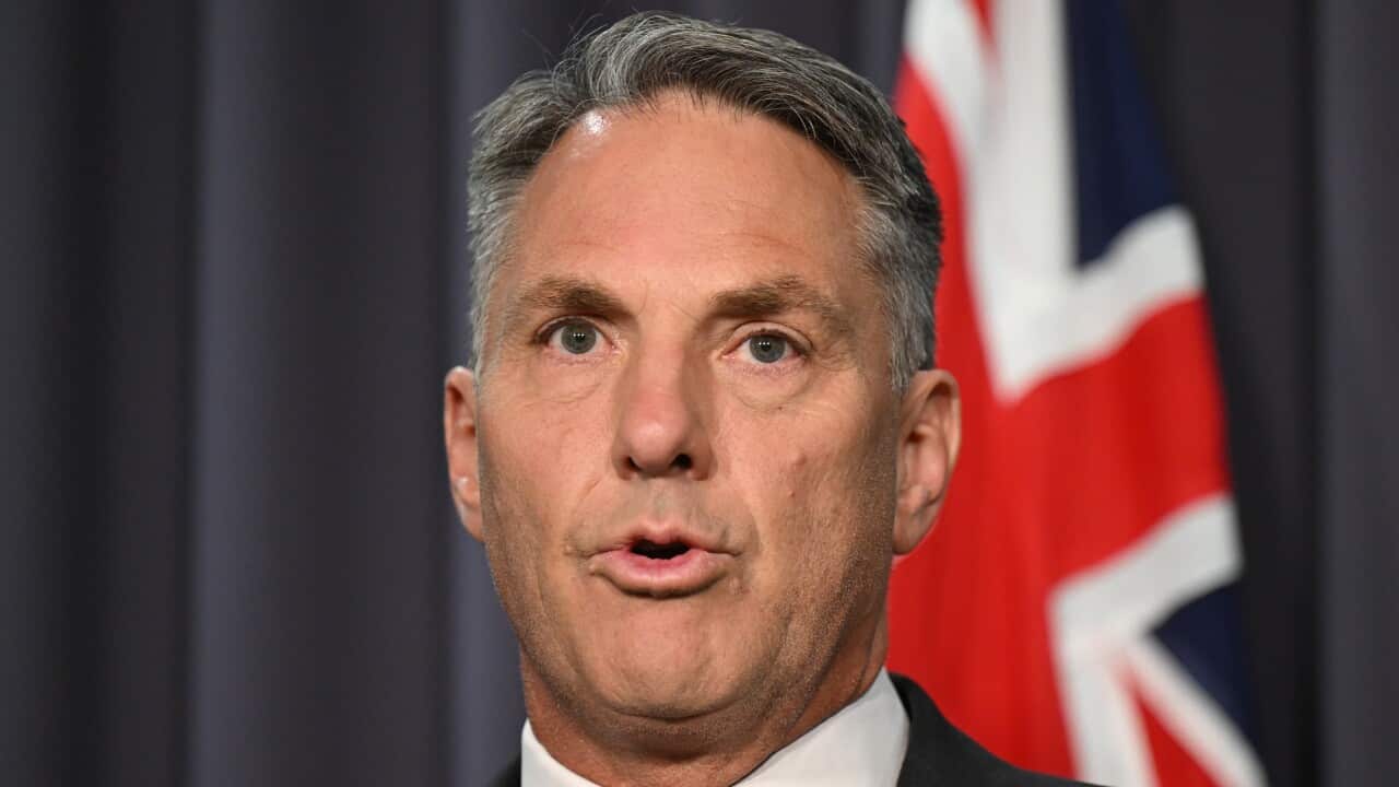 A man in a suit addresses the media