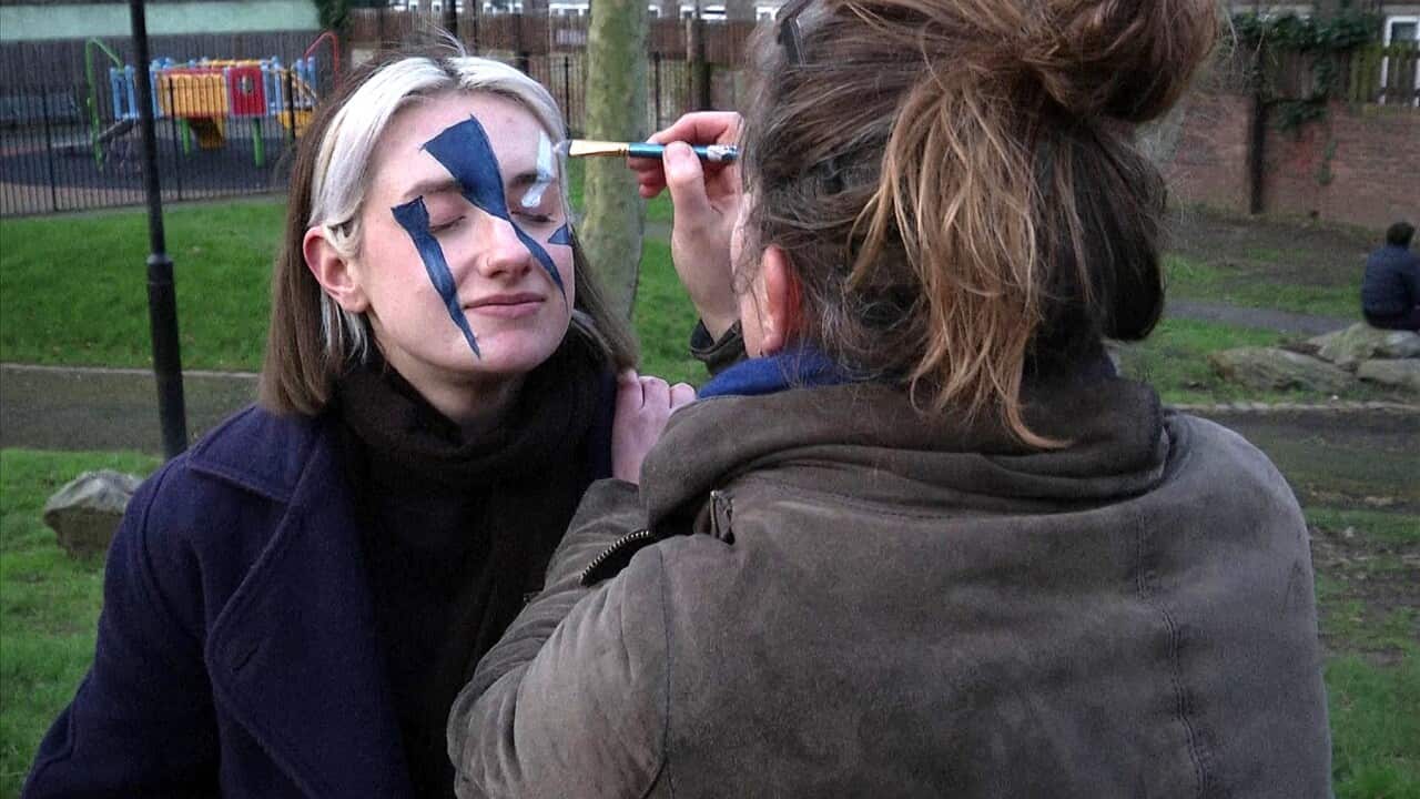 Members of the Dazzle Club work on their painted faces
