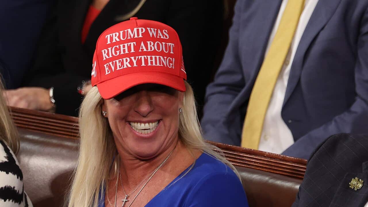 Marjorie Taylor Greene beaming and wearing a red "Trump was right about everything" cap.